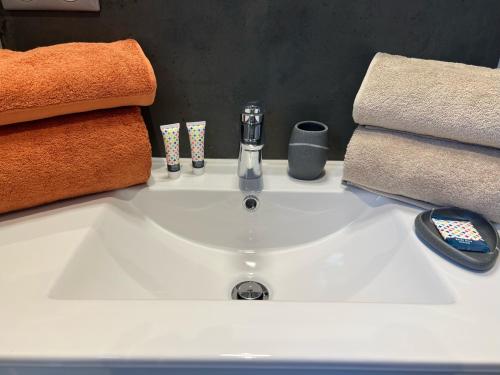 La salle de bains est pourvue d'un lavabo avec des serviettes et d'une télécommande. dans l'établissement Mas Orchis, à Cazevieille