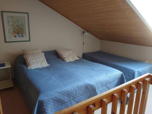 a bedroom with two beds with blue sheets in a attic at Rivitalon huoneisto Tahkolla in Tahkovuori