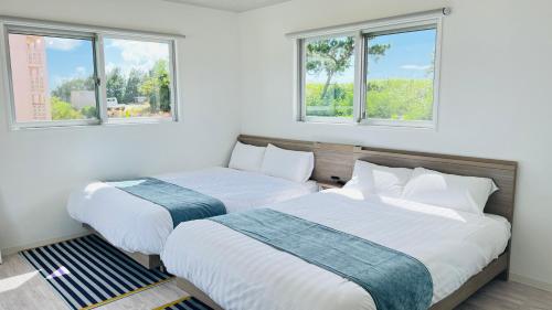 2 Betten in einem Zimmer mit 2 Fenstern in der Unterkunft Miyako Blue Villa Kugai in Miyako-jima