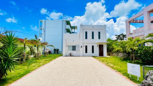 a white house with a driveway at Miyako Blue Villa Kugai in Miyako-jima