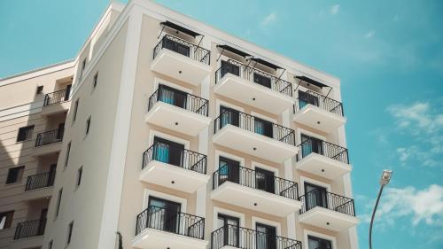 a tall white building with balconies on it at Kondo Hotel Allure in Budva