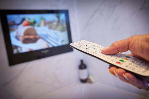 a person holding a remote control in front of a tv at Gwel an Mor in Portreath