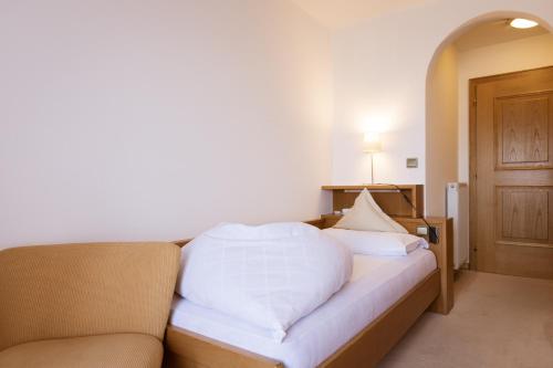 a bedroom with a bed and a couch and a door at B&B Hotel Mair am Turm in Tirolo