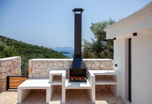 a fireplace on a patio with two white benches at Villa Dara and Todd in Sivota