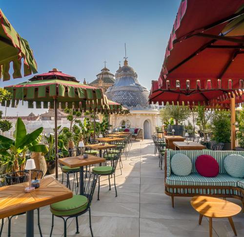 an outdoor restaurant with tables and chairs and umbrellas at Palacio Gran Vía, a Royal Hideaway Hotel in Granada