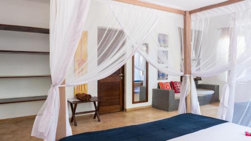 um quarto com uma cama de dossel e cortinas brancas em Raha Lodge Zanzibar Boutique Hotel em Jambiani