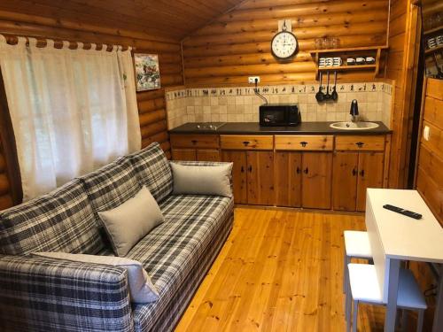 a living room with a couch and a kitchen at Cabaña de ensueño en el bosque y junto al mar in Miengo