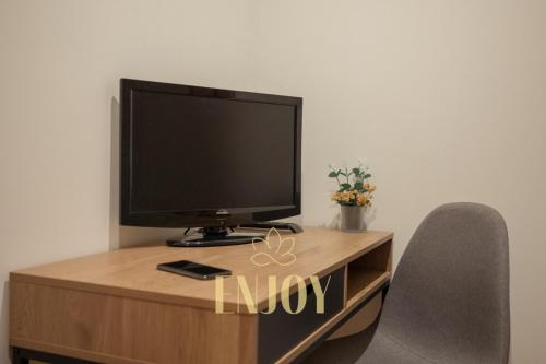 a tv sitting on top of a wooden desk with two chairs at Enjoy Flat by TonsdeVerde in Braga