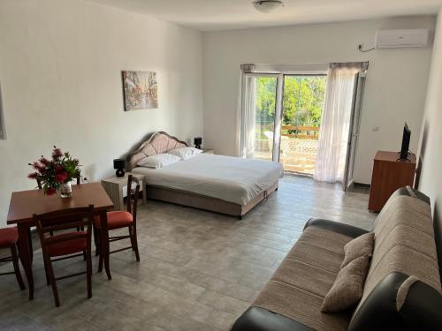 uma sala de estar com uma cama, uma mesa e um sofá em Apartman DAN em Bigovo
