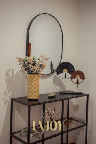 a black table with a mirror and a vase with flowers at Enjoy Flat by TonsdeVerde in Braga
