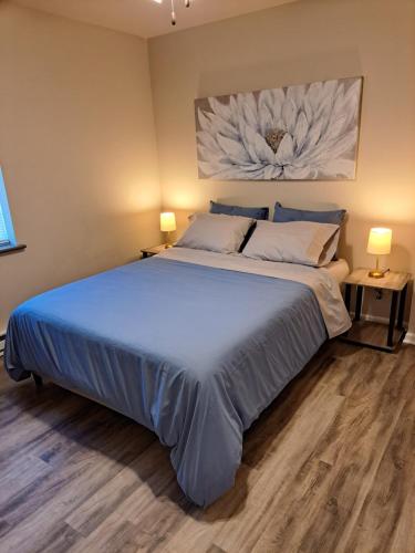 a bedroom with a large bed with blue sheets and two lamps at Burlington Getaway in Burlington