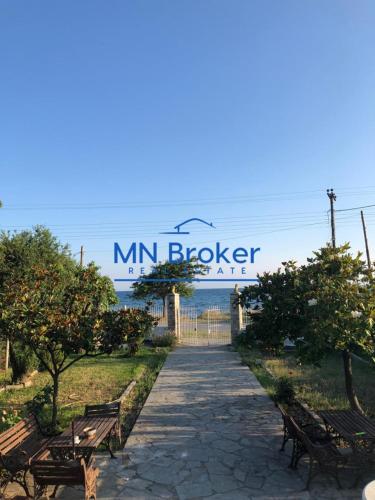 a walkway with benches and a sign that reads min broker at NA House 1 in Nea Kalikratia