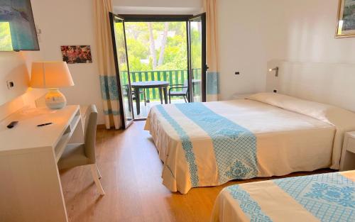 a bedroom with two beds and a table with a lamp at Hotel Dei Pini in Alghero