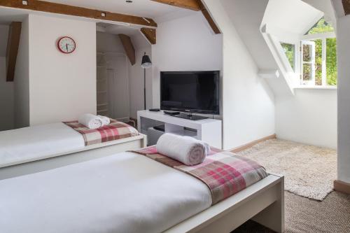 two beds in a white room with a tv at The Cors Country House in Laugharne