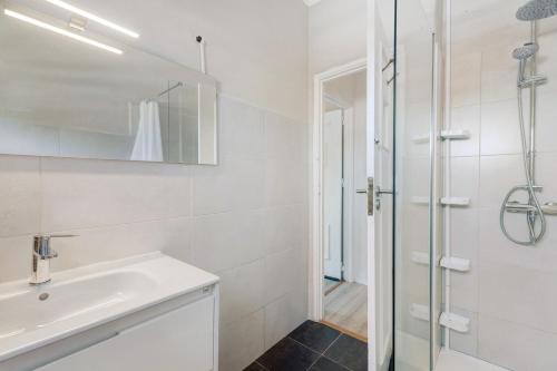 a white bathroom with a sink and a shower at Bisa's house in Estoril