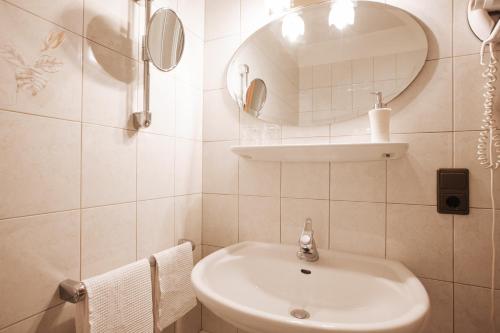 a white bathroom with a sink and a mirror at B&B Hotel Mair am Turm in Tirolo