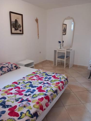 a bedroom with a bed with a floral comforter and a mirror at Karin Apartmani Hani in Gornji Karin
