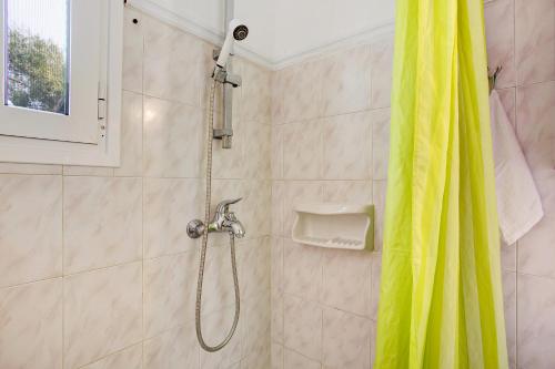 a shower with a yellow shower curtain in a bathroom at Areti Orfeas Apartment 7 in Vasilikos