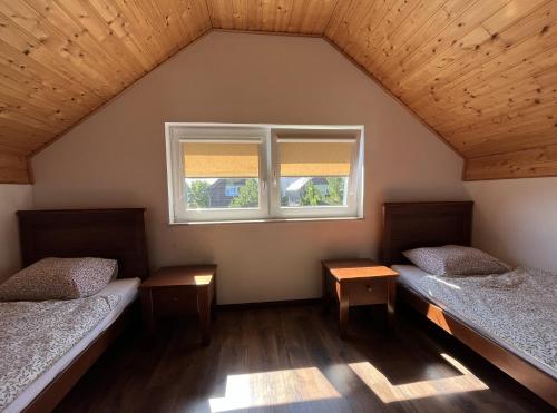 two beds in a room with a window at Sekret Łeba Dom i Domki in Łeba