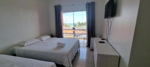 1 dormitorio con 2 camas y ventana con vistas en Pousada Litorânea, en São Luís