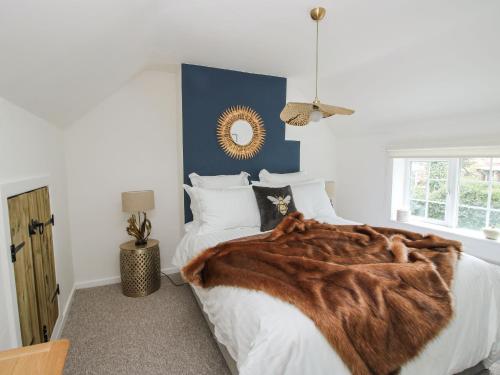 a bedroom with a bed with a fur blanket on it at Clematis Cottage in Shrewsbury
