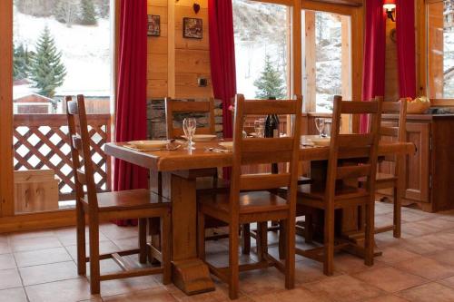 une salle à manger avec une table et des chaises en bois dans l'établissement L'Aiglon - spacious 2-bedroom apartment with log fire, à Sainte-Foy-Tarentaise