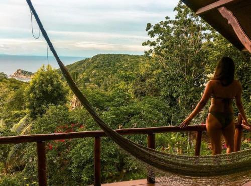 a woman in a bikini standing on a hammock looking at the forest at Tree House Bungalows Koh Tao in Koh Tao