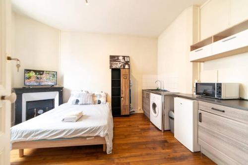 een slaapkamer met een bed en een keuken met een fornuis bij LA BELLE PAUSE - Studio Auxerre proche parking in Auxerre