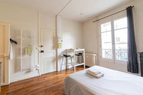 1 dormitorio con cama, ventana y escritorio en LA BELLE PAUSE - Studio Auxerre proche parking en Auxerre