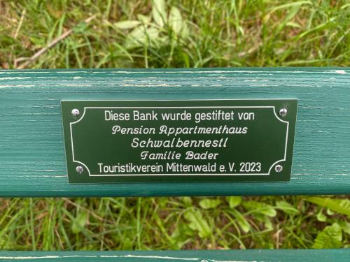 a sign on the back of a green bench at Alpenappartements Schwalbennestl in Mittenwald