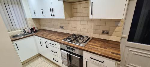 a small kitchen with white cabinets and a stove at Thorpe House Suites in Heeley