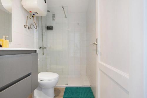 a white bathroom with a toilet and a shower at Piso Relax - Carpe Mundi in Corralejo