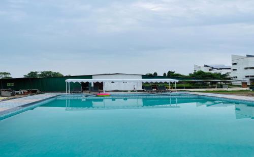 a large swimming pool with a pavilion in the background at Vasant Vihar Resort in Kevadia
