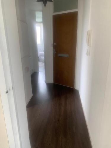 een lege hal met een deur en een houten vloer bij 1 Bed Apartment, Close to station in Londen