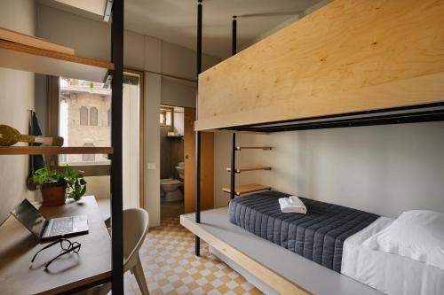 a bedroom with a bunk bed and a desk with a laptop at 'RE-Dama Hostel in Florence