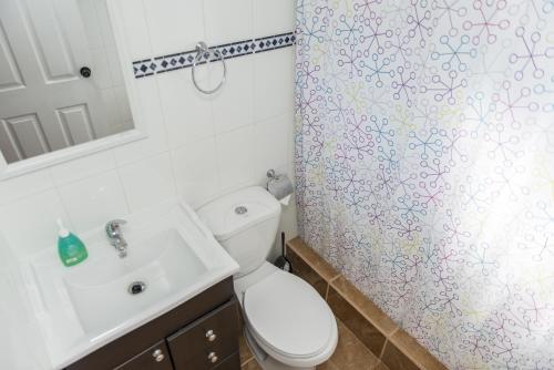 y baño con aseo, lavamanos y cortina de ducha. en Cabañas Don Gustavo, en La Serena