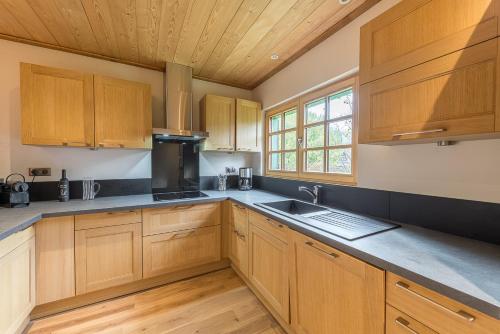 une cuisine avec des armoires en bois et un évier dans l'établissement ST JORIOZ-Chalet renove des Grands Champs proche lac et piste cycable- LLA Selections by Location lac Annecy, à Saint-Jorioz