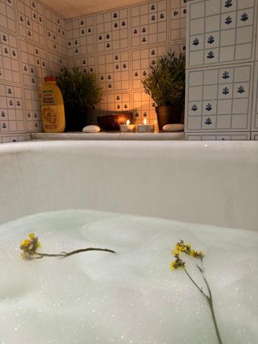 a bath tub filled with water with yellow flowers in it at Under the Castle - In the heart of the Old Town in Naxos Chora