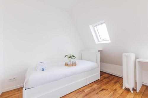 ein weißes Zimmer mit einem Bett und einem Fenster in der Unterkunft Cozy studio renovated Rue Bugeaud in Paris