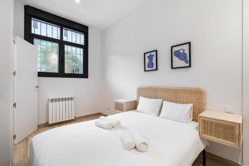 1 dormitorio con 1 cama blanca y 2 toallas en amplio duplex reformado, en Madrid