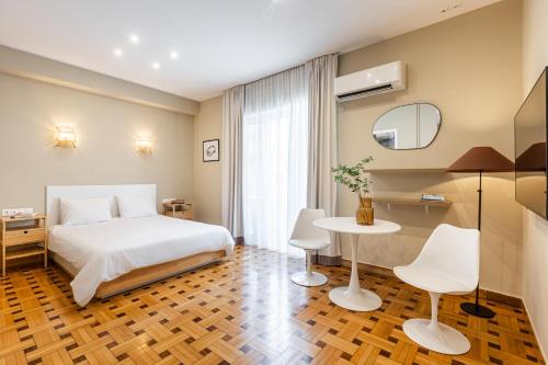 1 dormitorio con 1 cama, mesa y sillas en Kolonaki Suites by Olala Homes, en Atenas