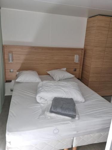 - un grand lit blanc avec un porte-monnaie noir dans l'établissement Location d'un mobil-home de 35 m² au Camping Les Sables d'Or - 4 étoiles avec grand parc aquatique, au Grau-dʼAgde