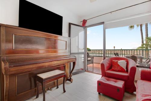a living room with a piano and a red chair at Dunes to explore and relax Wifi in Corralejo