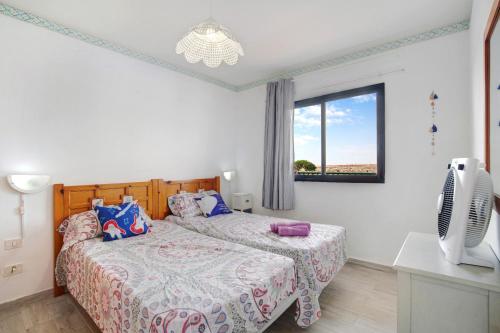 a bedroom with two beds and a tv and a window at Dunes to explore and relax Wifi in Corralejo