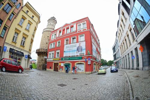 a red building on a city street with cars at Apartamenty Zamkowa in Jelenia Góra