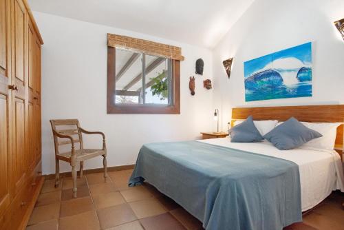 Casa al volcán de Lajares في لاجاريس: غرفة نوم بسرير وكرسي ونافذة
