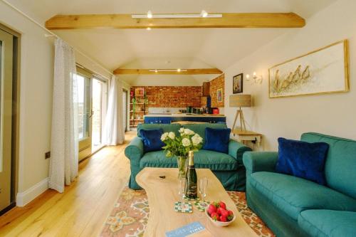 a living room with blue couches and a table at Alde Bay Farm - Oyster Catcher in Aldeburgh