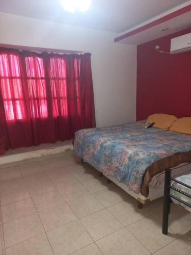 um quarto com cortinas vermelhas e uma cama num quarto em La Casa de Los Mellis.. em La Banda
