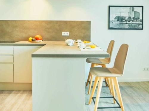 una cocina con una isla con 2 sillas y una encimera en Ohlerich Speicher App_ 03, en Wismar