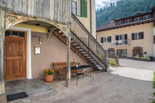 a building with a wooden door and a bench and stairs at Enrich Apartment in Ortisei
